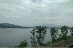 トンネルを出た後に、窓左側に登場する小沼(こぬま)の景色。やや右奥にあるのが北海道駒ヶ岳(渡島富士)。